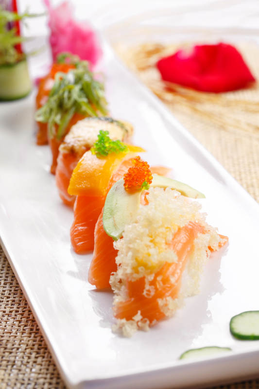 什锦三文鱼手握寿司摆放在草垫上图片