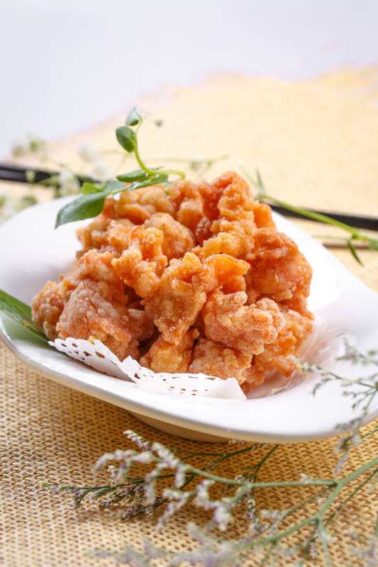 鹅颈瓷盘装的炸鸡块摆放在草垫上图片