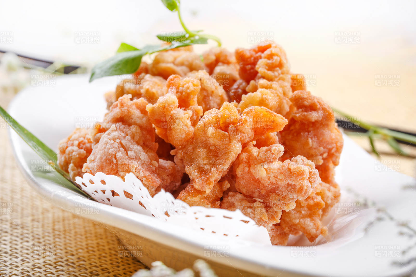 鹅颈瓷盘装的炸鸡块摆放在草垫上图片