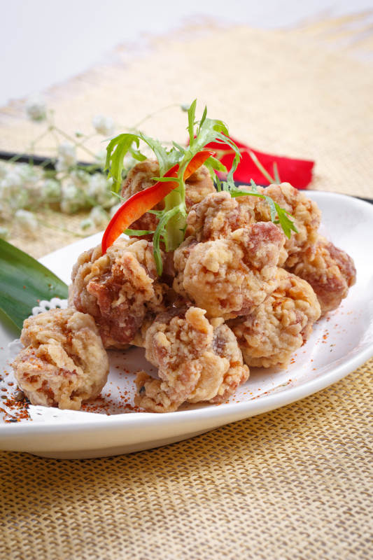 鹅颈瓷盘装的炸鸡块摆放在草垫上图片