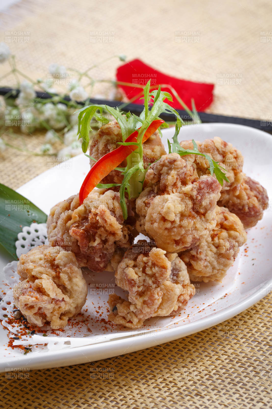 鹅颈瓷盘装的炸鸡块摆放在草垫上图片