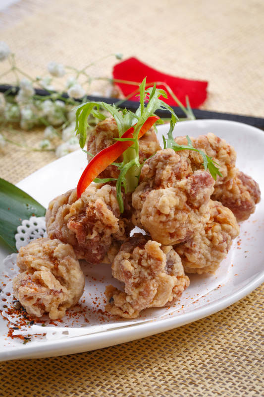 鹅颈瓷盘装的炸鸡块摆放在草垫上图片