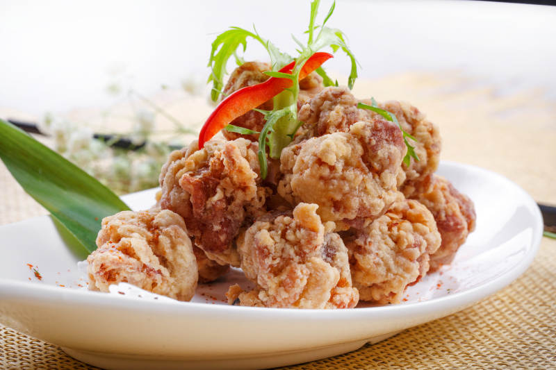 鹅颈瓷盘装的炸鸡块摆放在草垫上图片