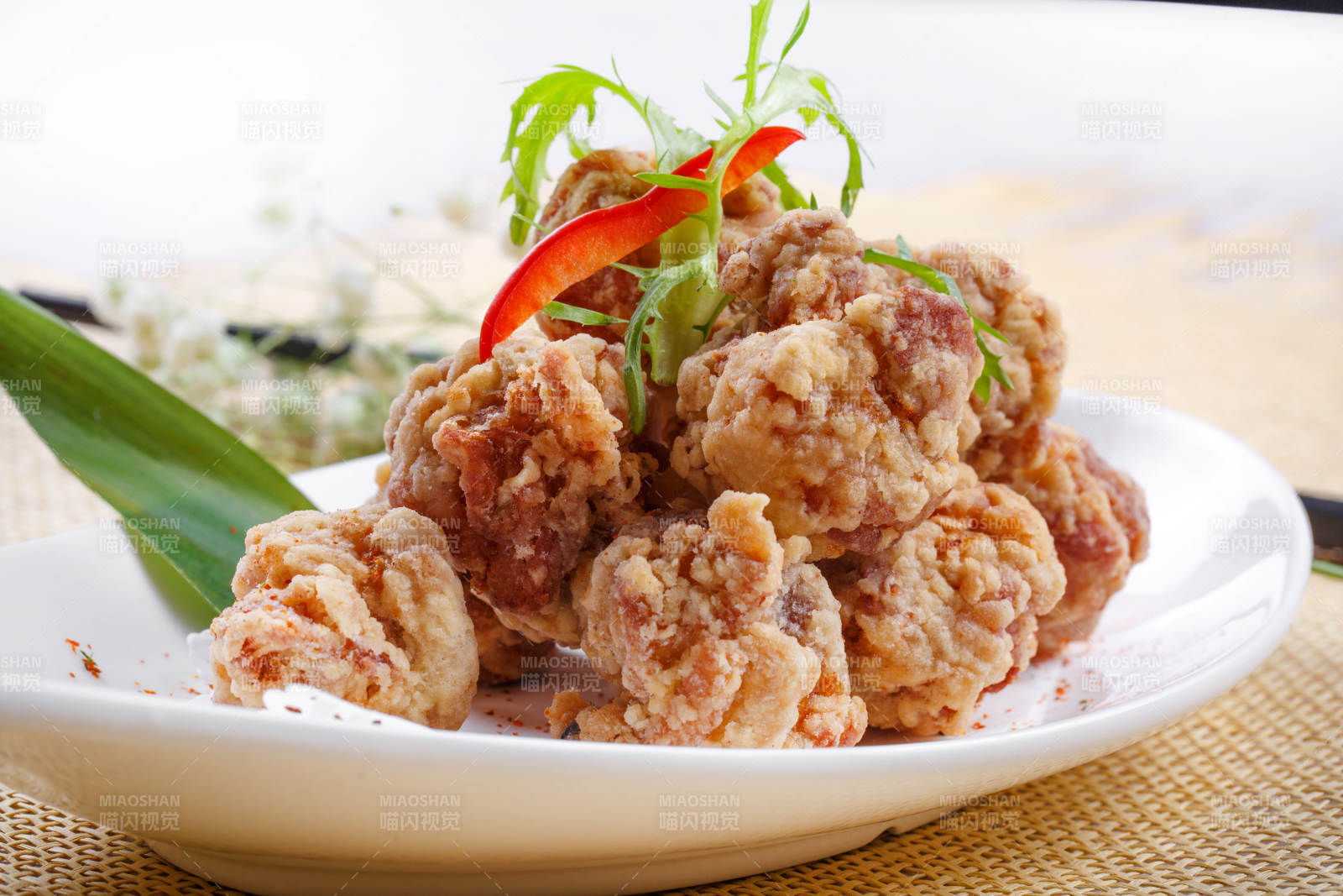 鹅颈瓷盘装的炸鸡块摆放在草垫上图片