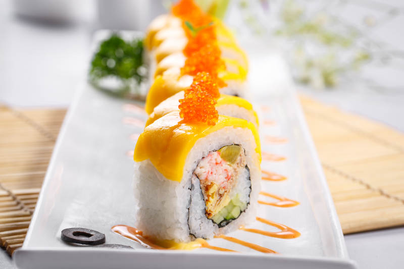 黄金甲蟹子寿司卷摆放在寿司帘上图片