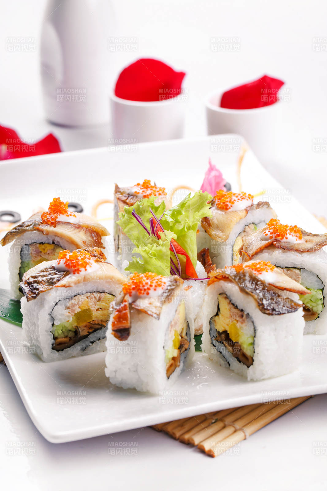 什锦鳗鱼手卷寿司摆放在寿司帘上图片