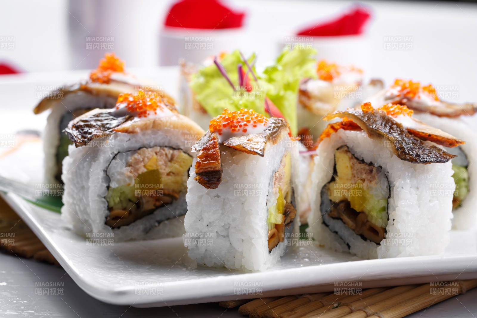 什锦鳗鱼手卷寿司摆放在寿司帘上图片