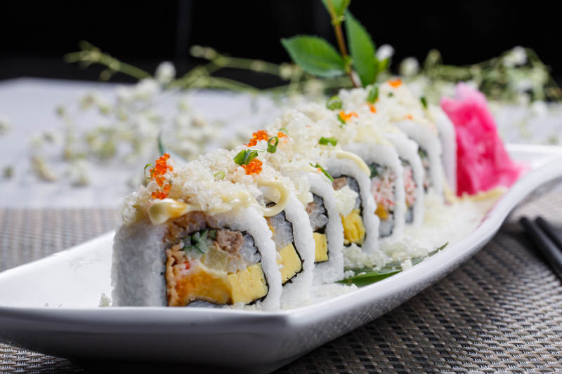 长方形瓷盘装的脆脆卷寿司摆放在餐垫上图片