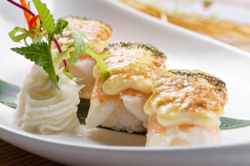 芝士焗鲜虾手握寿司摆放在寿司帘上图片