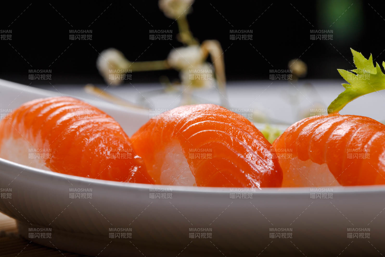 三文鱼手握寿司摆放在寿司帘上图片