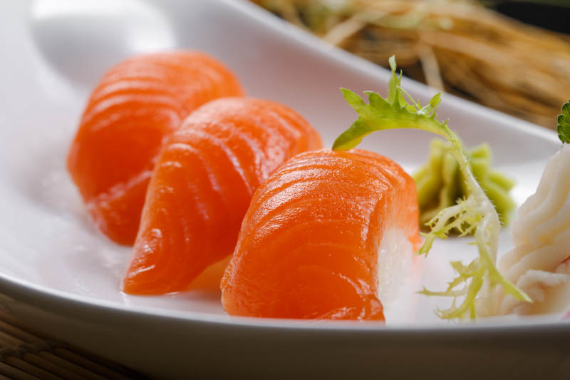 三文鱼手握寿司摆放在寿司帘上图片