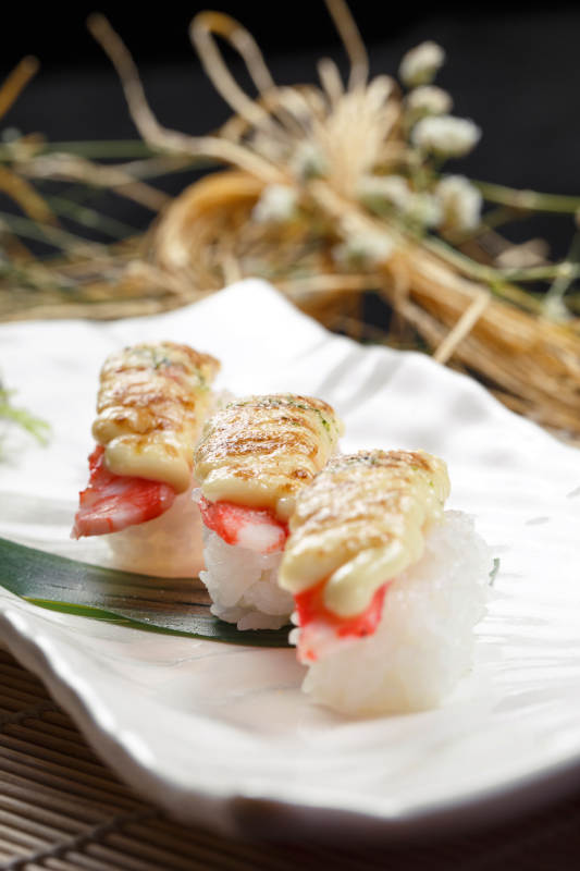 芝士焗蟹钳肉手握寿司摆放在寿司帘上图片