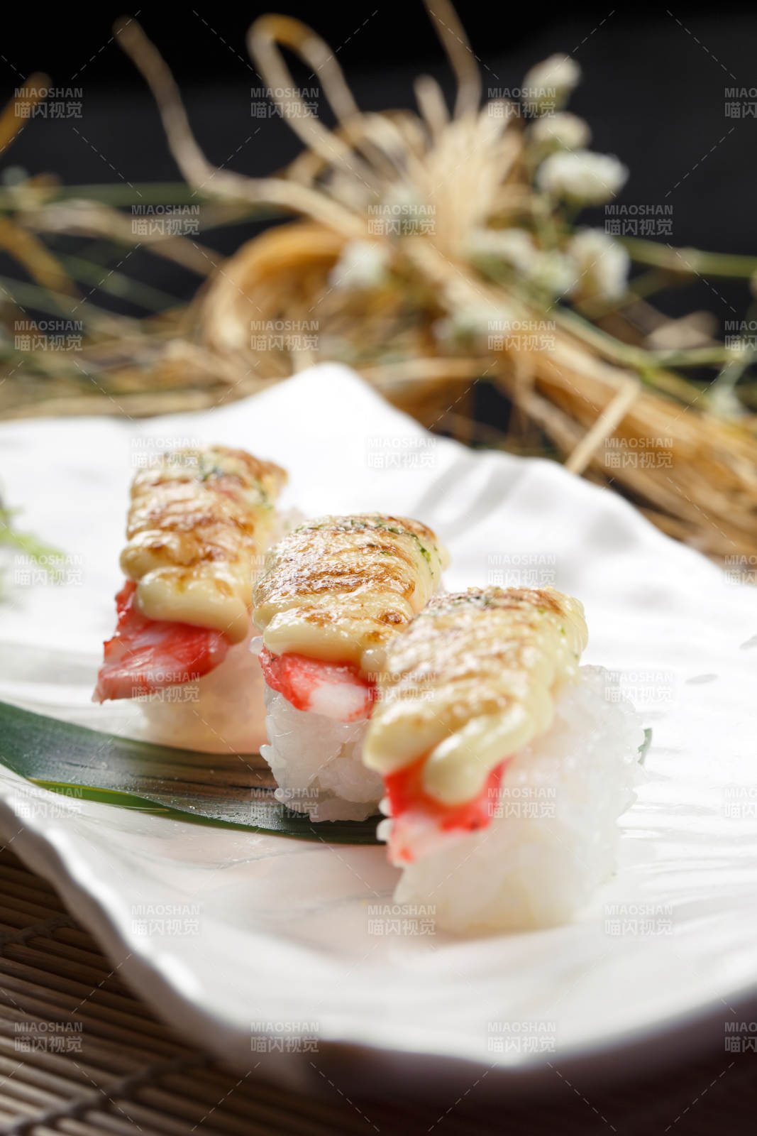 芝士焗蟹钳肉手握寿司摆放在寿司帘上图片