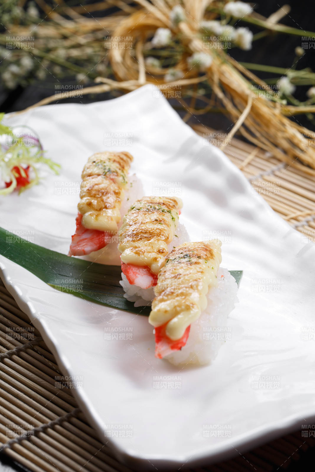 芝士焗蟹钳肉手握寿司摆放在寿司帘上图片