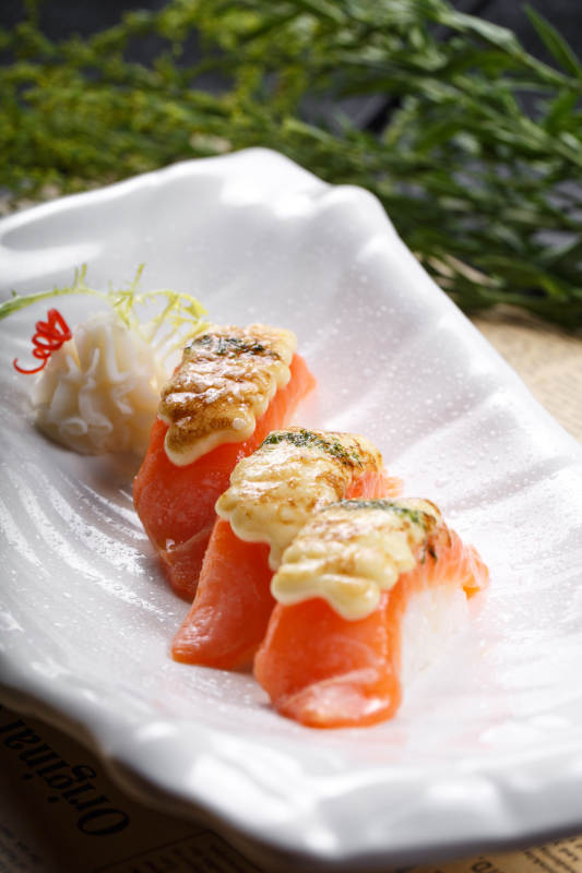 芝士焗三文鱼手握寿司摆放在英文包装纸上图片