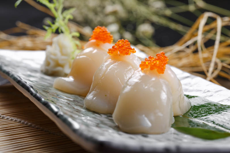 照烧带子蟹子手握寿司摆放在寿司帘上图片