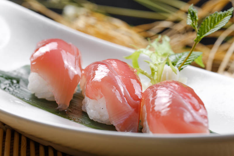 金枪鱼手握寿司摆放在寿司帘上图片