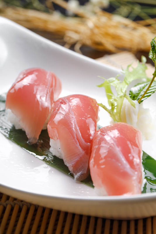 金枪鱼手握寿司摆放在寿司帘上图片