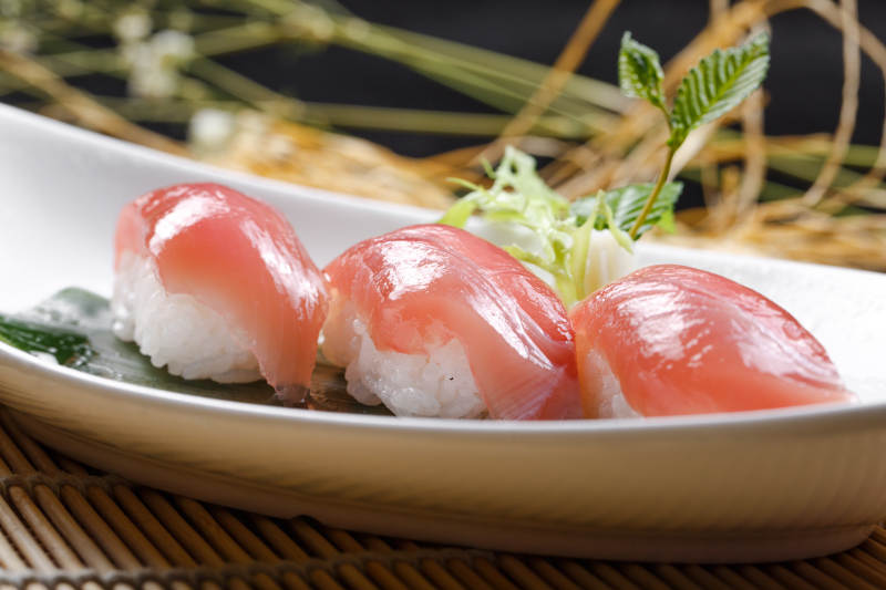 金枪鱼手握寿司摆放在寿司帘上图片