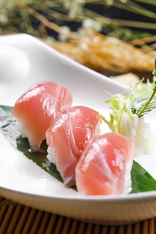 金枪鱼手握寿司摆放在寿司帘上图片