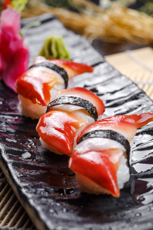 北极贝手握寿司摆放在寿司帘上图片