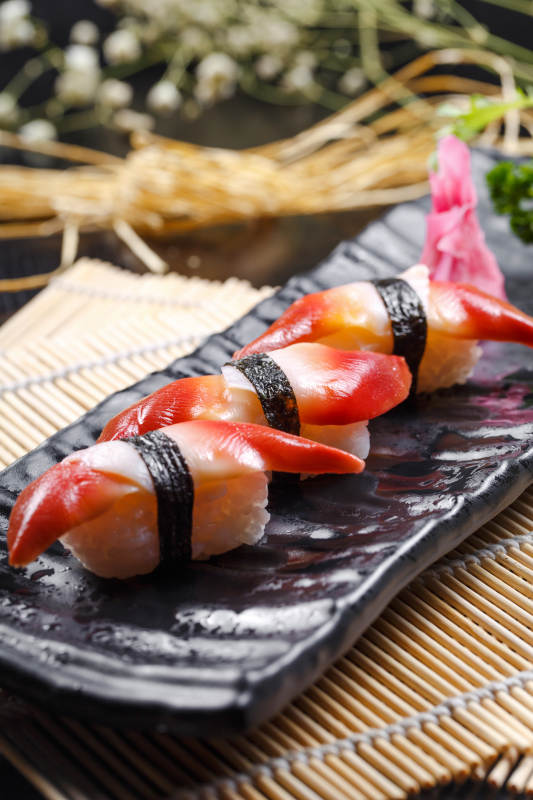 北极贝手握寿司摆放在寿司帘上图片