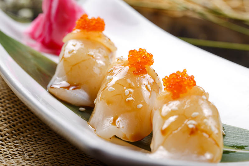 照烧带子蟹子手握寿司摆放在寿司帘上图片