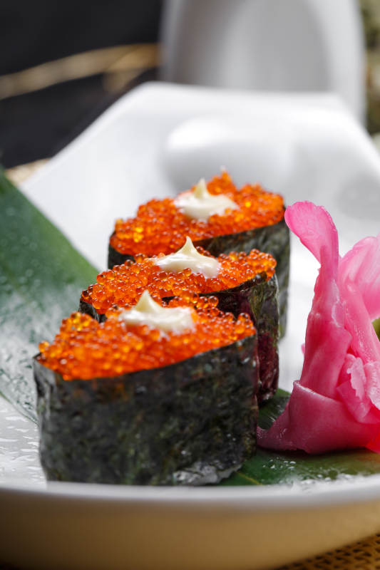 鹅颈瓷盘装的蟹子军舰手握寿司摆放在石头上图片