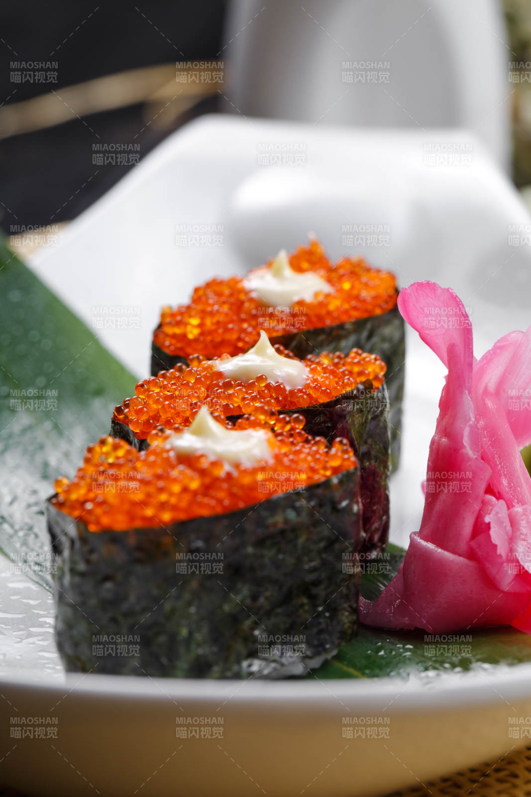 鹅颈瓷盘装的蟹子军舰手握寿司摆放在石头上图片