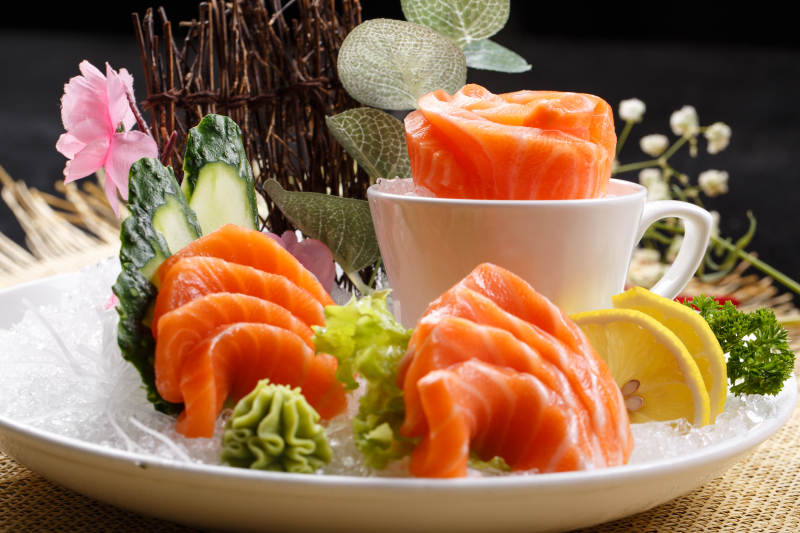 三文鱼刺身摆放在草垫上图片