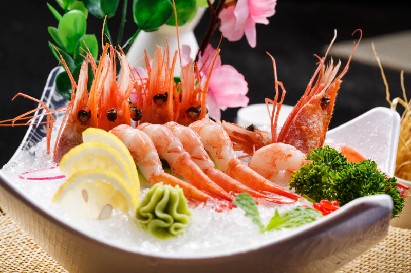 北极甜虾刺身摆放在草垫上图片