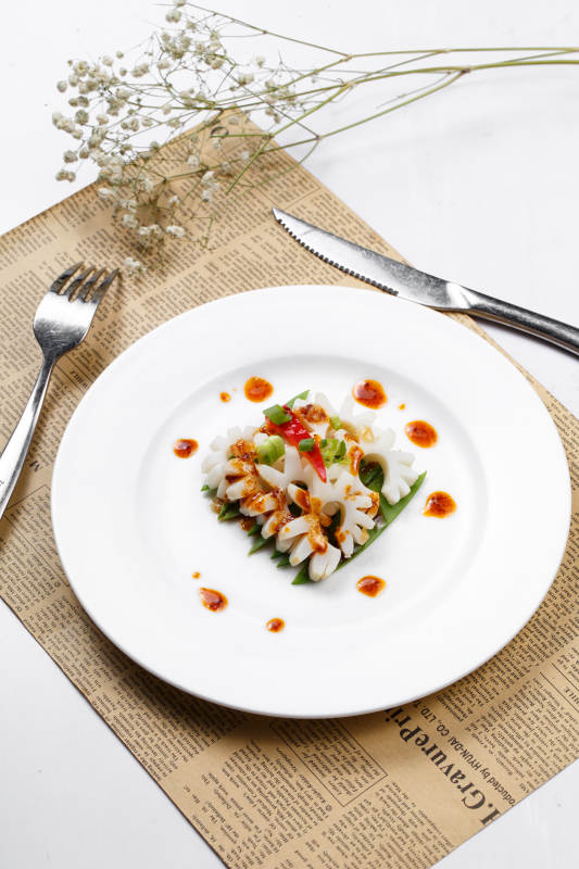 日式铁板煎鱿鱼卷摆放在英文包装纸上图片