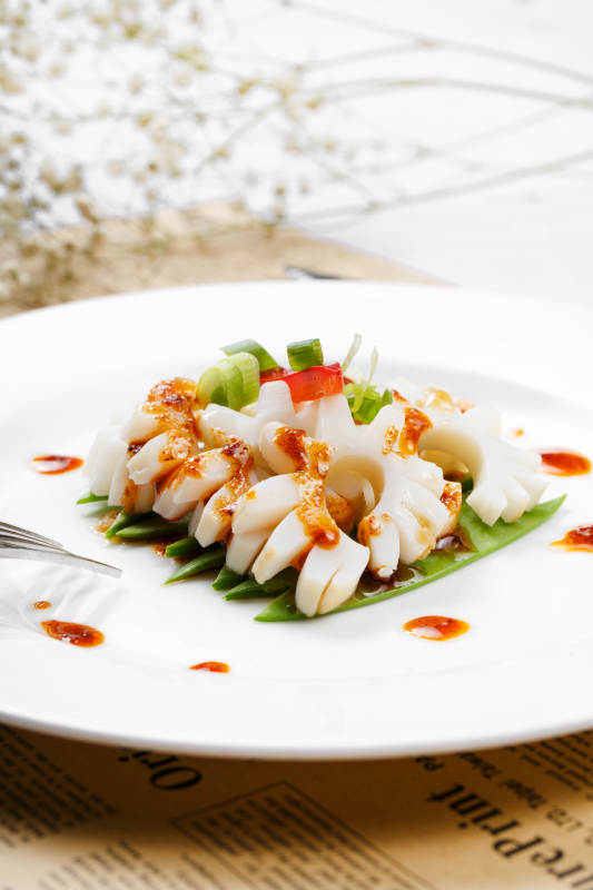 日式铁板煎鱿鱼卷摆放在英文包装纸上图片