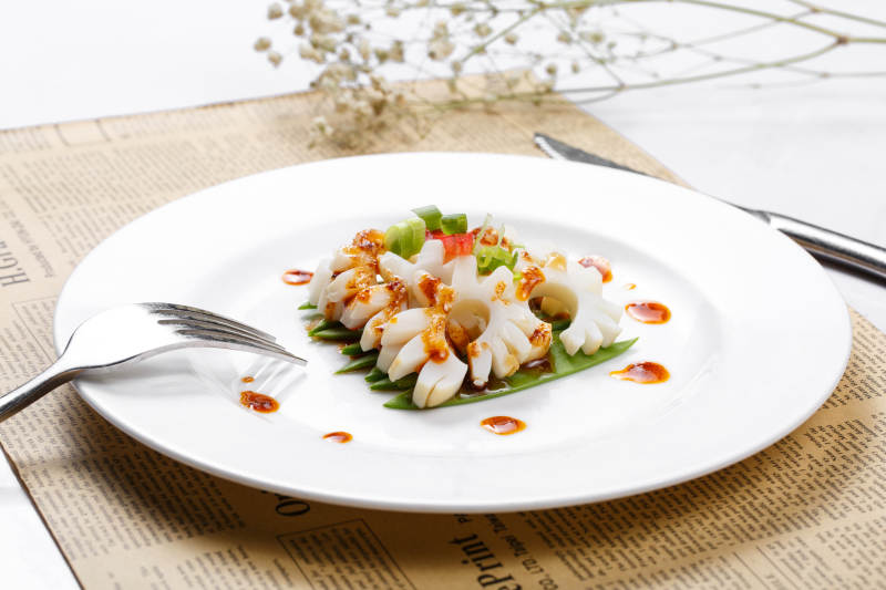 日式铁板煎鱿鱼卷摆放在英文包装纸上图片