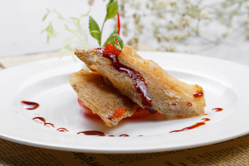 铁板煎格陵兰鳕鱼摆放在英文包装纸上图片