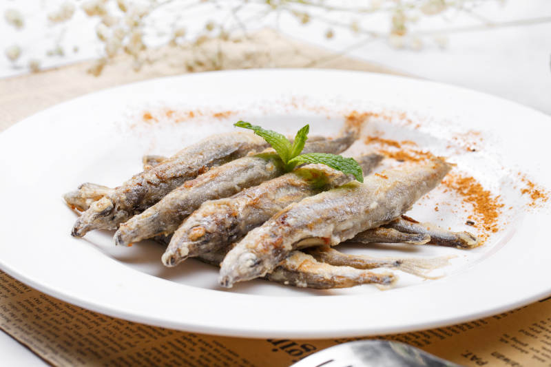 日式铁板煎椒盐多春鱼摆放在英文包装纸上图片