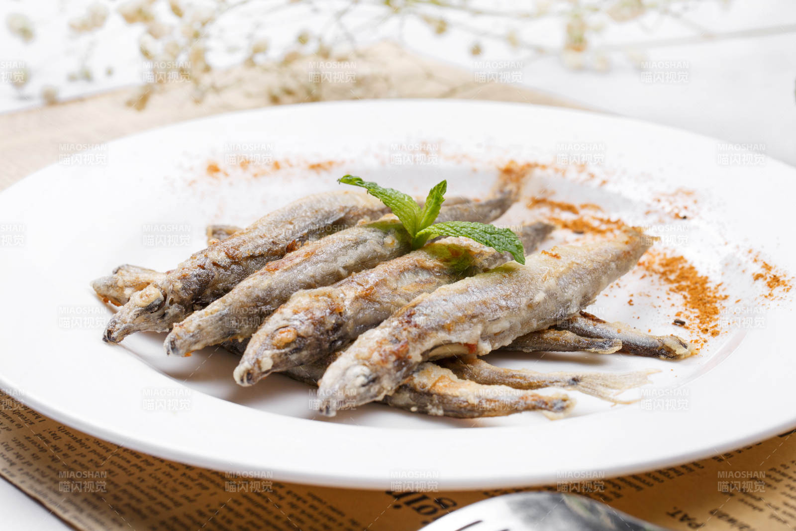 日式铁板煎椒盐多春鱼摆放在英文包装纸上图片