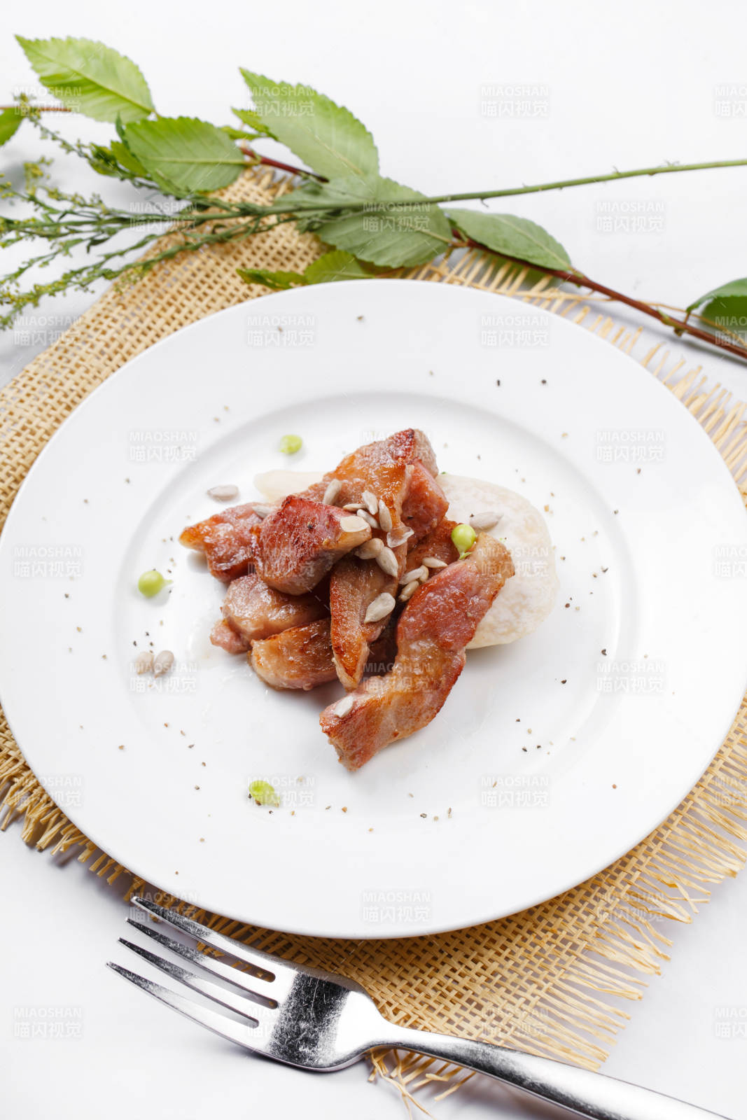 圆形白瓷盘装的铁板煎牛腹肉摆放在草垫上图片