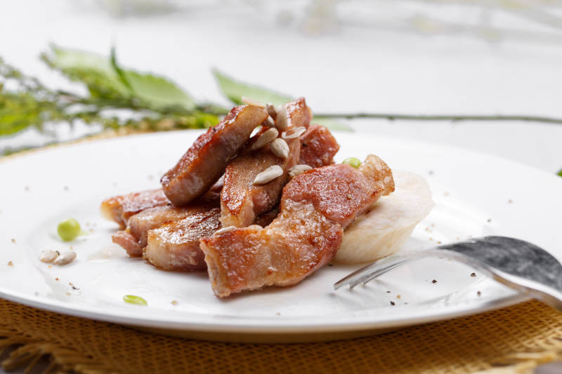 圆形白瓷盘装的铁板煎牛腹肉摆放在草垫上图片