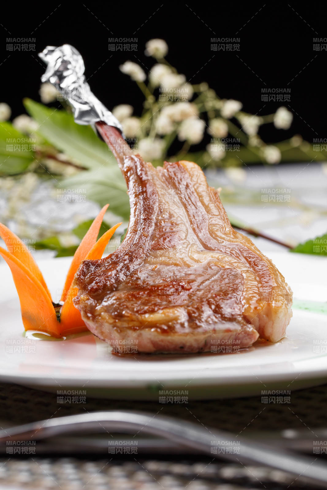 圆形白瓷盘装的波尔多法式铁板羊排摆放在餐垫上图片