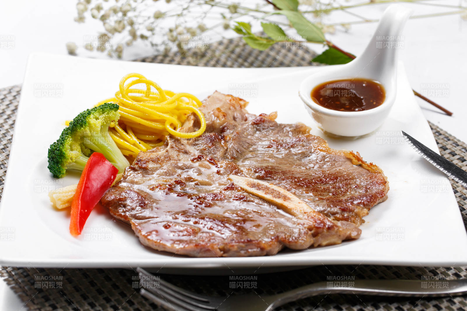 方形瓷盘装的新西兰T骨牛排摆放在餐垫上图片