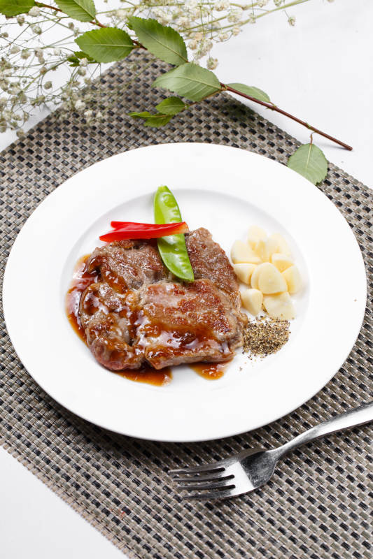 黑椒酱铁板煎蒜香猪排摆放在餐垫上图片