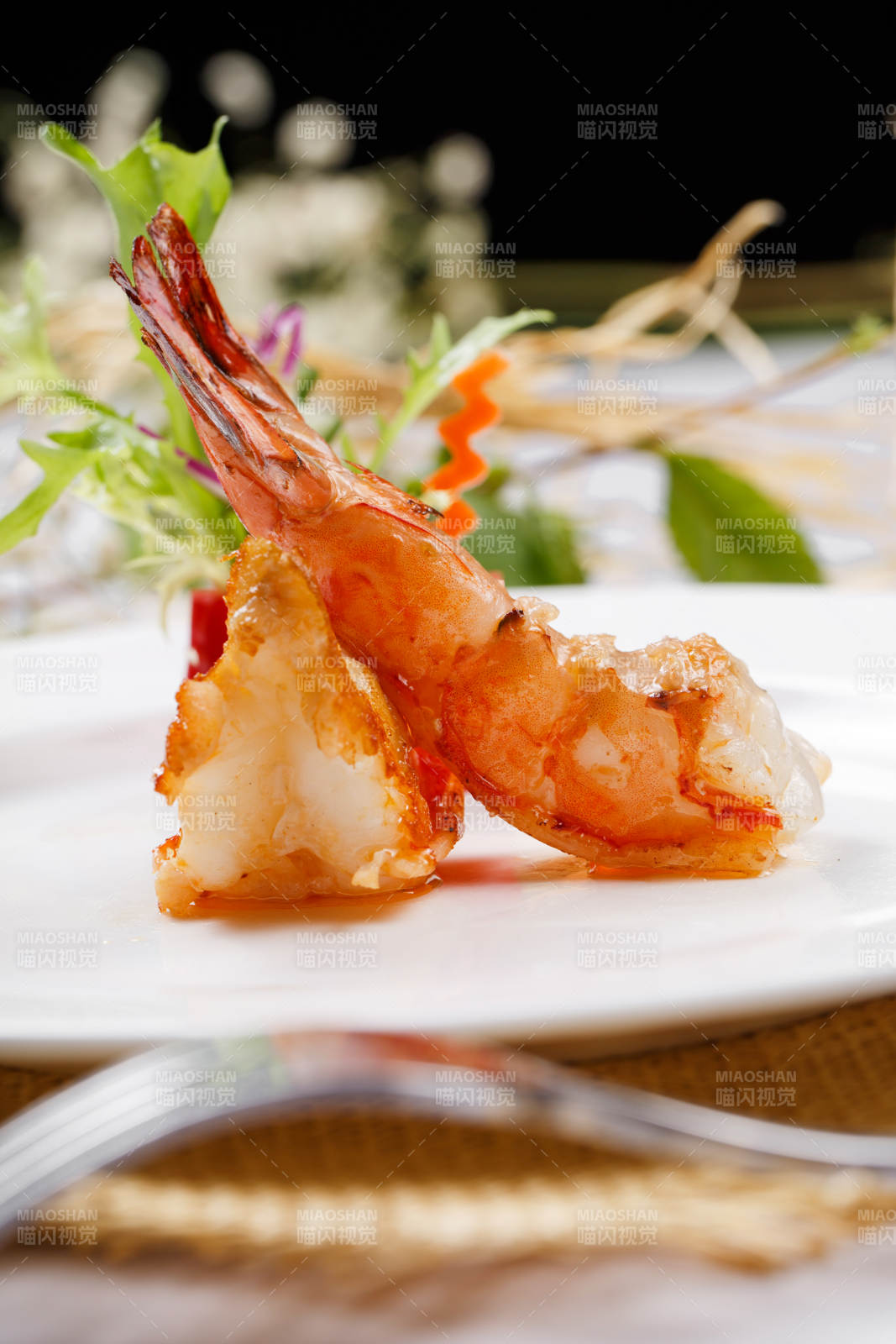 圆形白瓷盘装的铁板深海大明虾摆放在草垫上图片