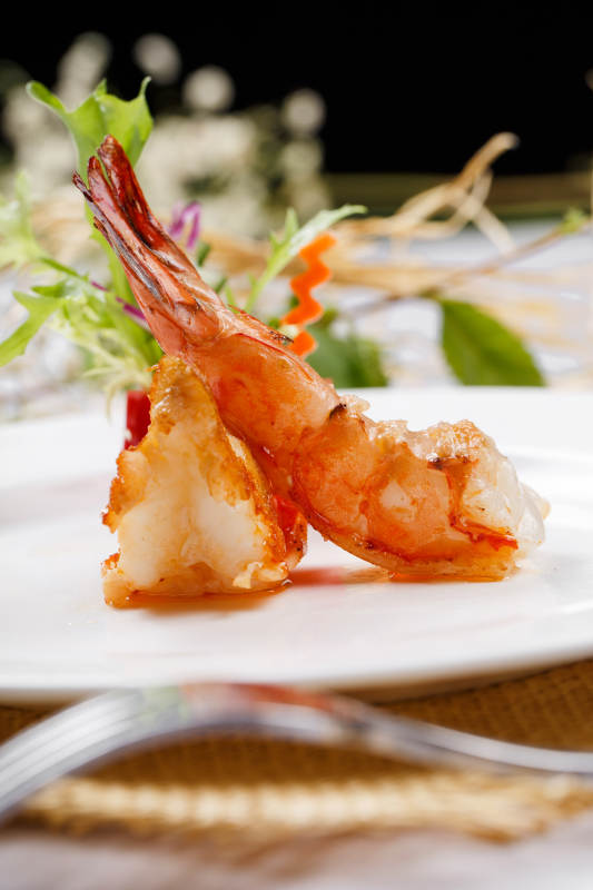 圆形白瓷盘装的铁板深海大明虾摆放在草垫上图片