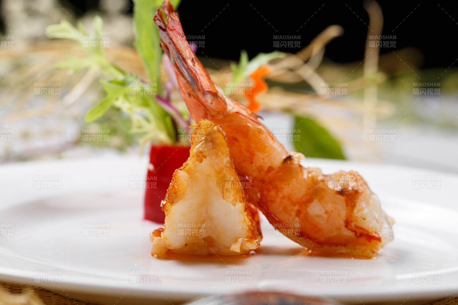 圆形白瓷盘装的铁板深海大明虾摆放在草垫上图片