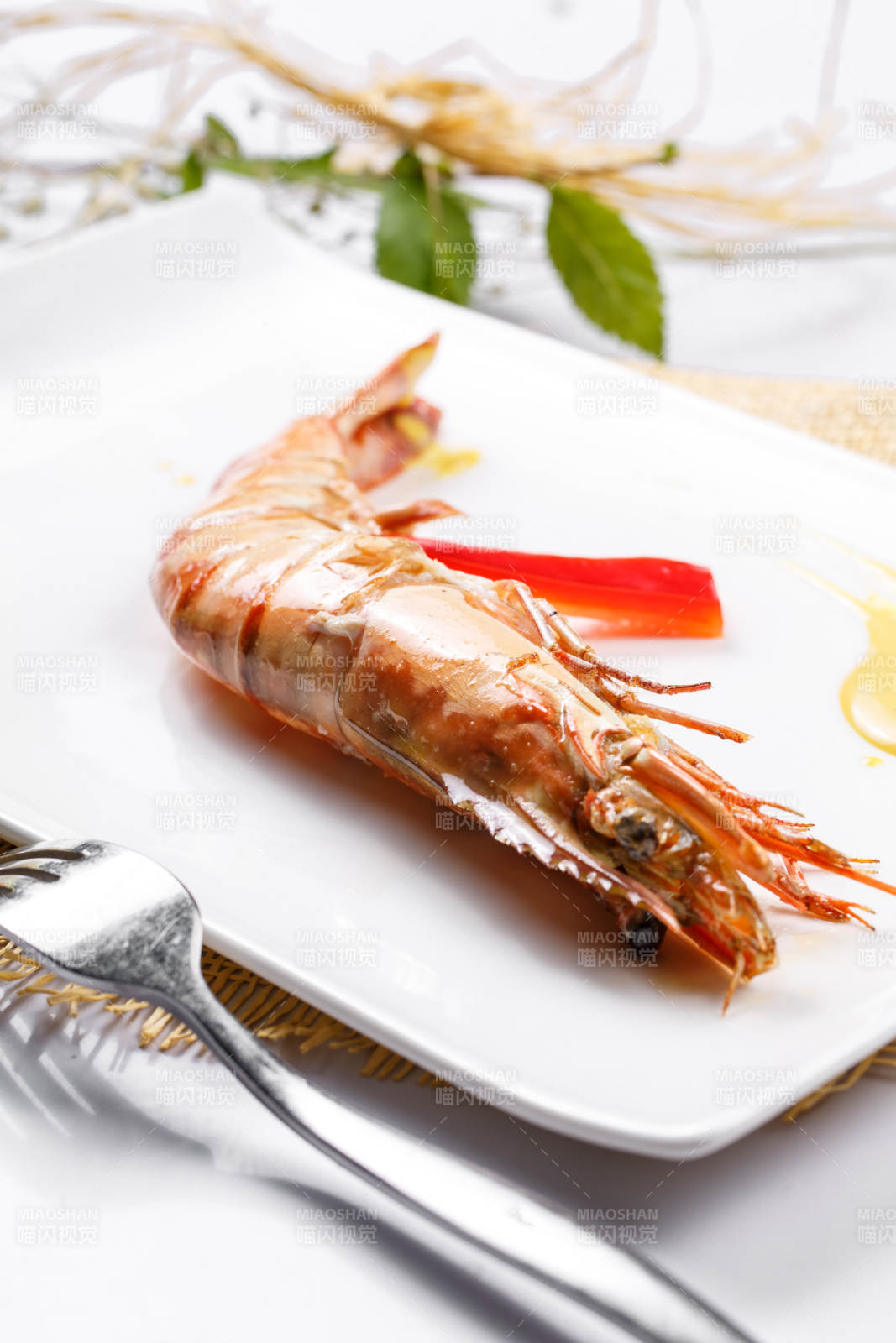 长方形瓷盘装的铁板野生明虾皇摆放在草垫上图片