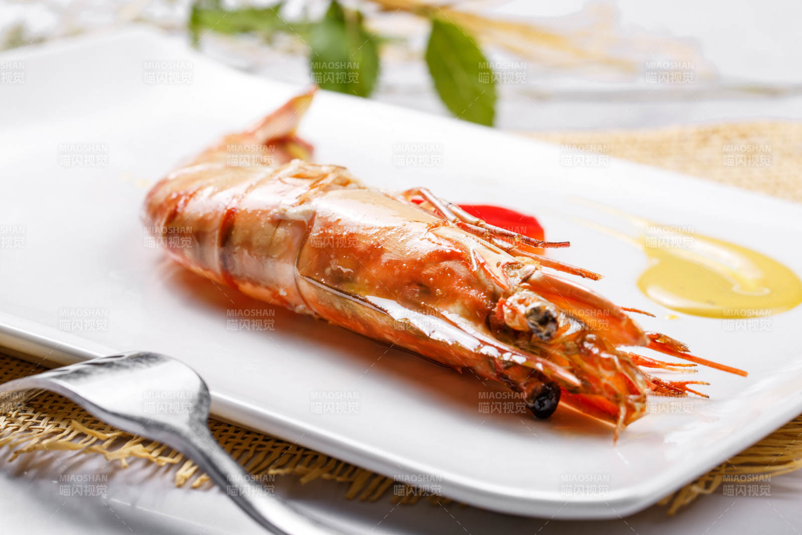 长方形瓷盘装的铁板野生明虾皇摆放在草垫上图片