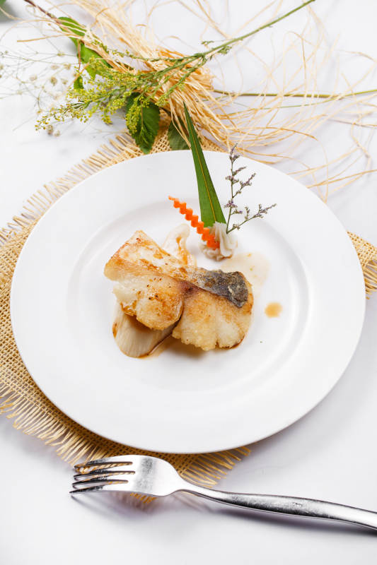 白色圆盘装的俄罗斯深海龙鳕鱼摆放在草垫上图片