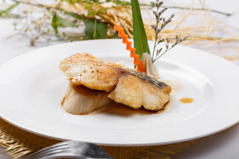 白色圆盘装的俄罗斯深海龙鳕鱼摆放在草垫上图片