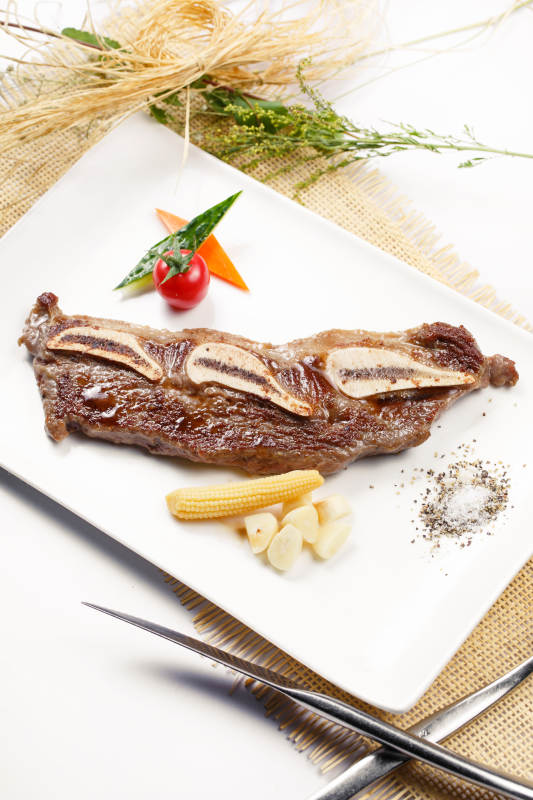 日式铁板带骨小牛排摆放在草垫上图片